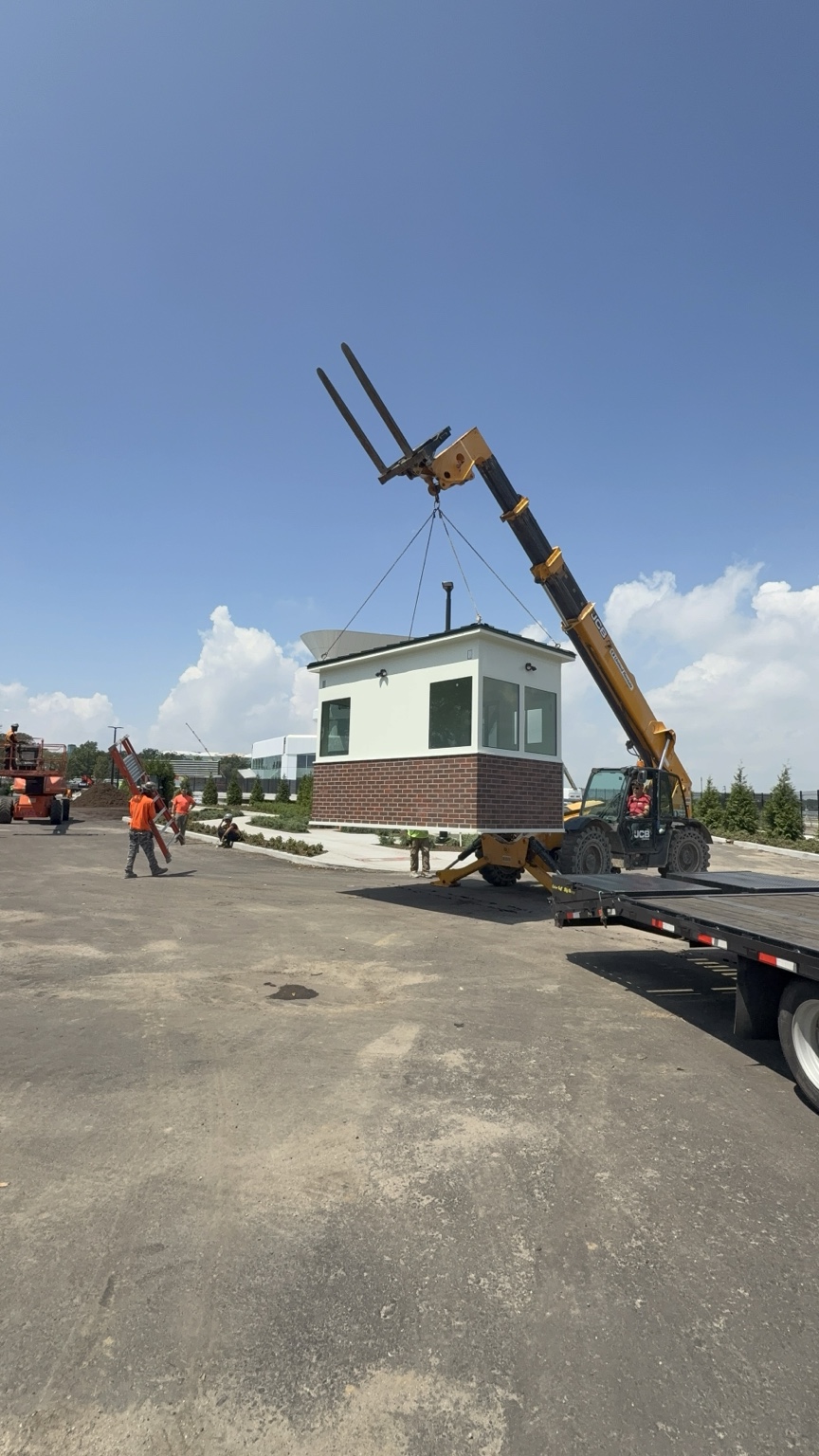 Modular building lifted beside a flatbed at a jobsite