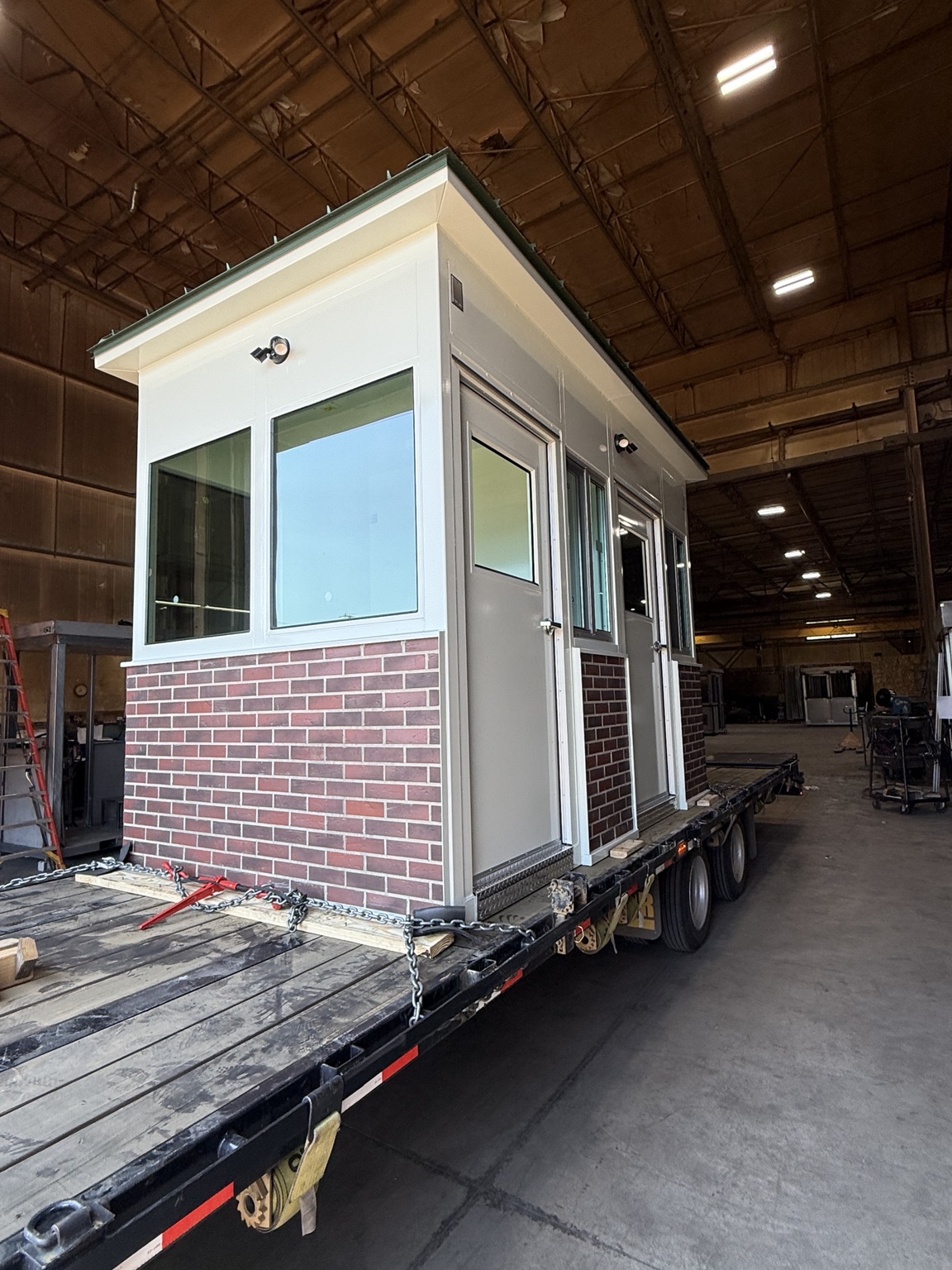A modular building secured on a flatbed trailer